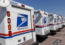 Ballot Delivery Tied To Voter Lists? Row of USPS mail trucks parked in a lot