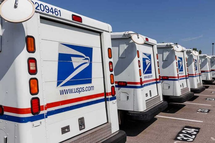 shutterstock_1475396903 Row of USPS mail trucks parked in a lot