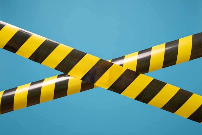 shutterstock_1629980767 caution tape crossing on blue background
