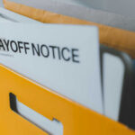 A yellow folder containing a layoff notice and other documents