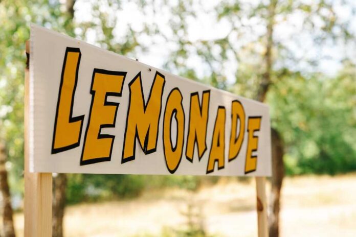 An,Empty,Lemonade,Stand,Ready,For,Children,To,Start,Selling Lemonade stand sign with bold yellow letters outdoors