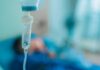 Why America Outsources Ebola Care Close-up of an IV drip in a hospital setting with a patient in the background