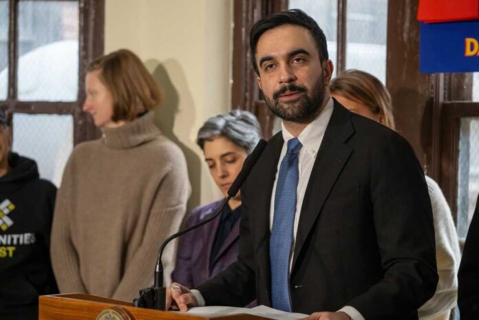 New,York,City,Mayor,Zohran,Mamdani,Holds,A,Press,Briefing Man in suit speaking at a podium with people standing behind