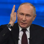 man in suit speaking with raised hand