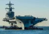 Aircraft carrier guided by tugboats in a harbor