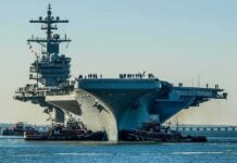 Aircraft carrier guided by tugboats in a harbor