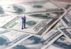 Cuban Torches Khanna’s Billionaire Hit Miniature businessman standing on US dollar bills