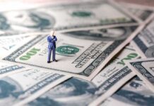 Cuban Torches Khanna’s Billionaire Hit Miniature businessman standing on US dollar bills