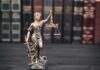 Health Titan Slain—Confession Upends Case Lady Justice statue with scales in front of law books