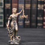 Lady Justice statue with scales in front of law books