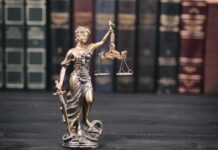 Health Titan Slain—Confession Upends Case Lady Justice statue with scales in front of law books
