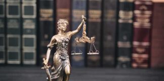 Lady Justice statue with scales in front of law books
