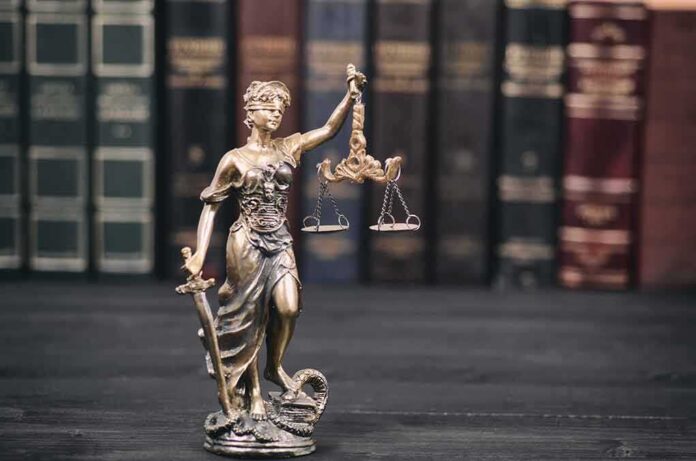 shutterstock_1112412905 Lady Justice statue with scales in front of law books