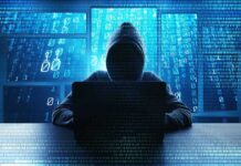 License To Hack: DOJ Orchestrates Payback Hooded figure using a laptop in front of glowing code