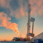 Oil drilling rig at sunset releasing steam