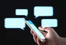 Hand holding smartphone with chat bubbles on dark background
