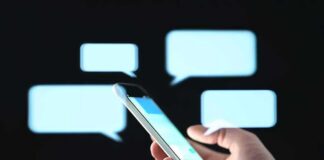 Hand holding smartphone with chat bubbles on dark background