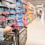 Shopper pushing a cart down a supermarket aisle