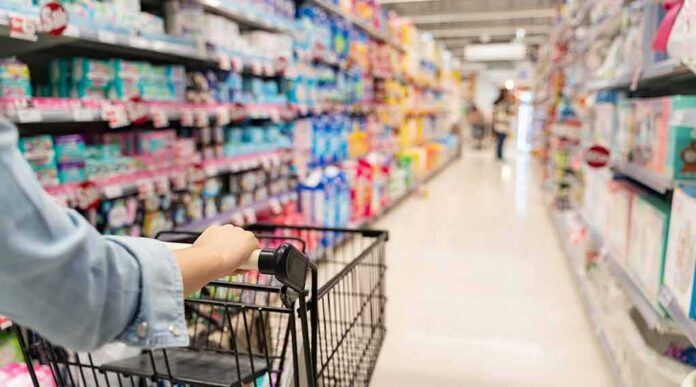 shutterstock_1537502423 Shopper pushing a cart down a supermarket aisle