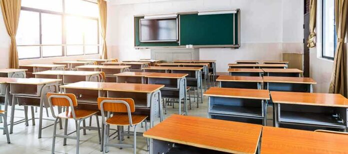 shutterstock_1717498237 Empty classroom with rows of desks and a chalkboard