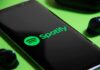 Algorithmic Muzzle For AI Musicians Smartphone showing Spotify app logo with wireless earbuds nearby