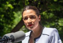 Women’s Sports Line Drawn — AOC Protests woman speaking at an outdoor microphone