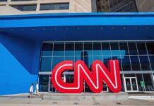 Exterior view of the CNN building with a large red logo and blue facade