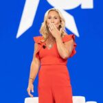 Woman in red jumpsuit on stage blowing a kiss