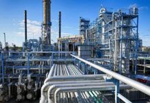 Big Oil Balks: Venezuela ‘Uninvestable’ Industrial refinery with pipelines and distillation towers under blue sky