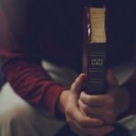 Person holding a closed Bible while seated