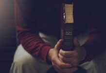 Faith Leader’s Loan Grab—Taxpayers Burned Person holding a closed Bible while seated