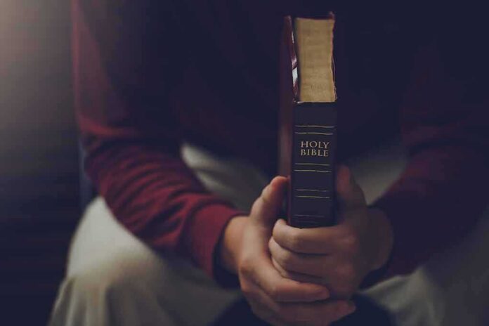 shutterstock_2317399153 Person holding a closed Bible while seated