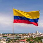 Quake Rubble Hides Unexpected Survivors Colombian flag waving over a coastal city skyline