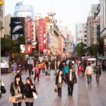 Crowded shopping street with pedestrians and storefronts