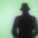 Silhouette of a person in a hat behind textured green glass