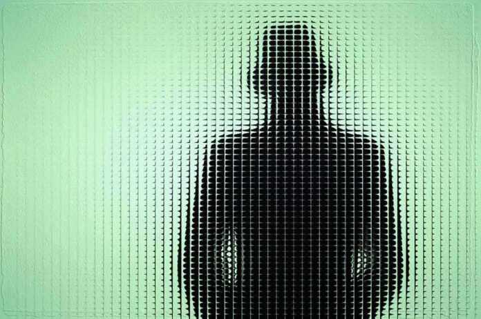 Silhouette of a person in a hat behind textured green glass