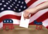 Hand casting ballot between Republican elephant and Democratic donkey