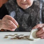 Elderly person counting coins on a table