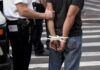 Teen Arrested After Beverly Hills Bloodshed police officer detains person with hands zip-tied behind back
