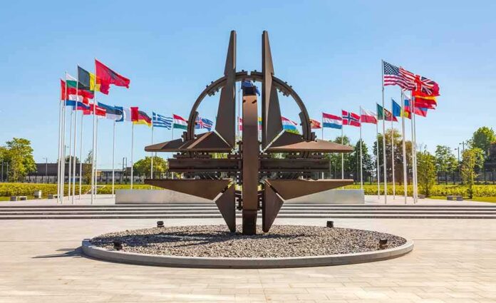 Metal sculpture with surrounding national flags in a plaza