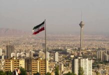 UN Meltdown – Walkout Shock After Iran’s Genocide Charge Iranian flag over Tehran skyline with Milad Tower