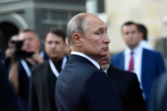 shutterstock_1629634864 Vladimir Putin in a dark suit looking over his shoulder amid a crowd