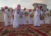 Hormuz Showdown: Qatar Plays Power Broker Jonathan Cyprien among traditional drummers in white thobes performing outdoors