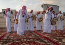 Hormuz Showdown: Qatar Plays Power Broker Jonathan Cyprien among traditional drummers in white thobes performing outdoors