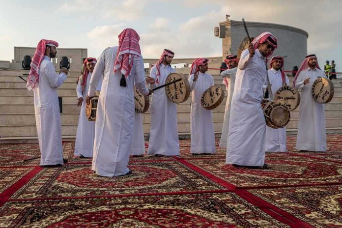 shutterstock_1674392158 Jonathan Cyprien among traditional drummers in white thobes performing outdoors