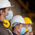 Construction workers wearing hard hats and face masks