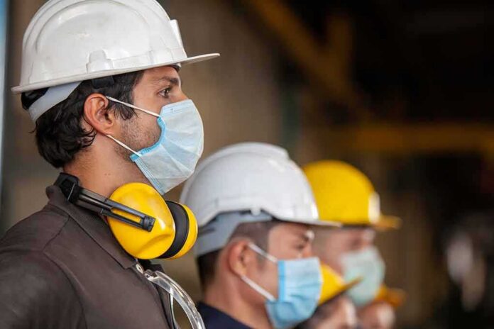 shutterstock_1685136613 Construction workers wearing hard hats and face masks