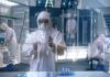 Week-Four Jolt: Aging Markers Flip Scientist in hazmat suit using a transparent digital tablet in a lab
