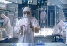 Scientist in hazmat suit using a transparent digital tablet in a lab