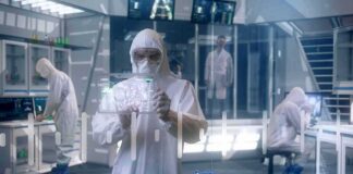 Scientist in hazmat suit using a transparent digital tablet in a lab